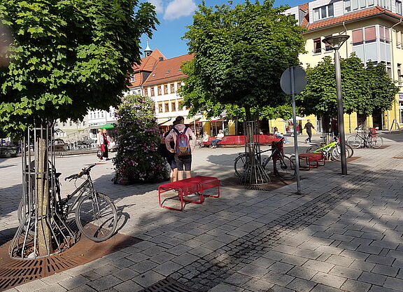 Fahrräder stehen an Baumschutzgittern in Suhl, im Hintergrund der Dianabrunnen